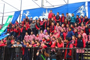 Los alumnos de básica alentando a sus compañeros desde la galería.